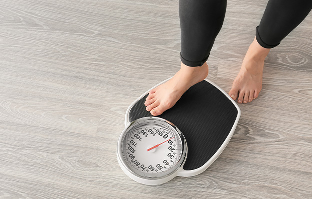 VGH-Woman-with-scales-at-home.-Weight-loss-concept-ss-5-NMN-Manages-Healthy-Weight