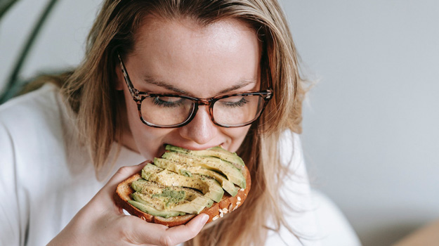 blonde-woman-eating-avocado-on-toast-What-to-Eat-When-Feeling-Weak-on-Period-px